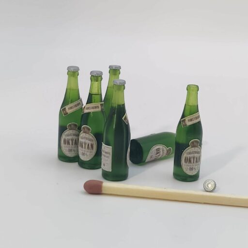 Miniature ølflasker i grøn klar resin med Oktan-øl-etiketter og sølvfarvede kapsler i skala 1/9