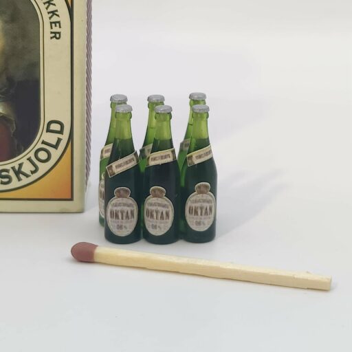 Miniature ølflasker i grøn klar resin med Oktan-øl-etiketter og sølvfarvede kapsler i skala 1/9